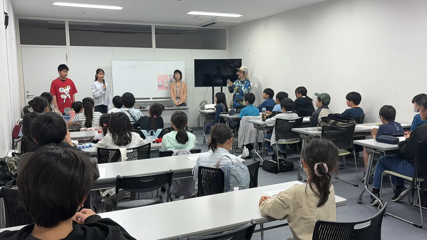 会議室の前に立って参加者に説明をする子どもたち