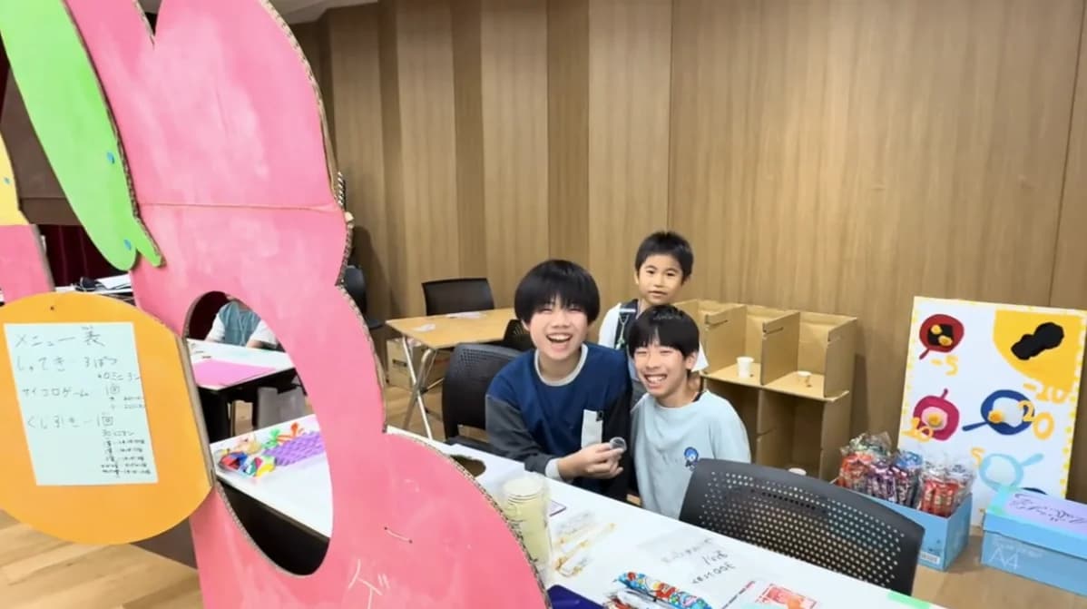 ピンクの段ボール看板の前で笑顔を見せる子どもたち