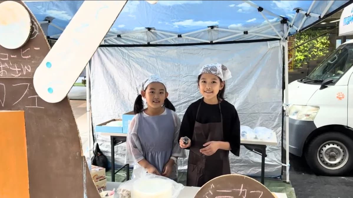 ミニカフェのテントの前に立つ子ども店員