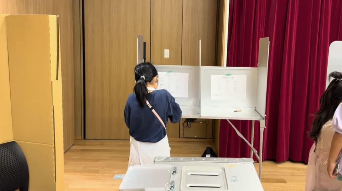 投票記載台で一票を書いている子ども