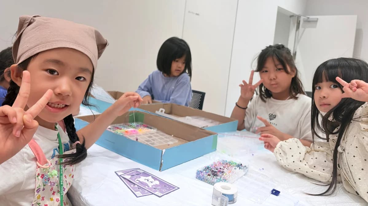 ビーズ工作のお店でピースサインをする子どもたち