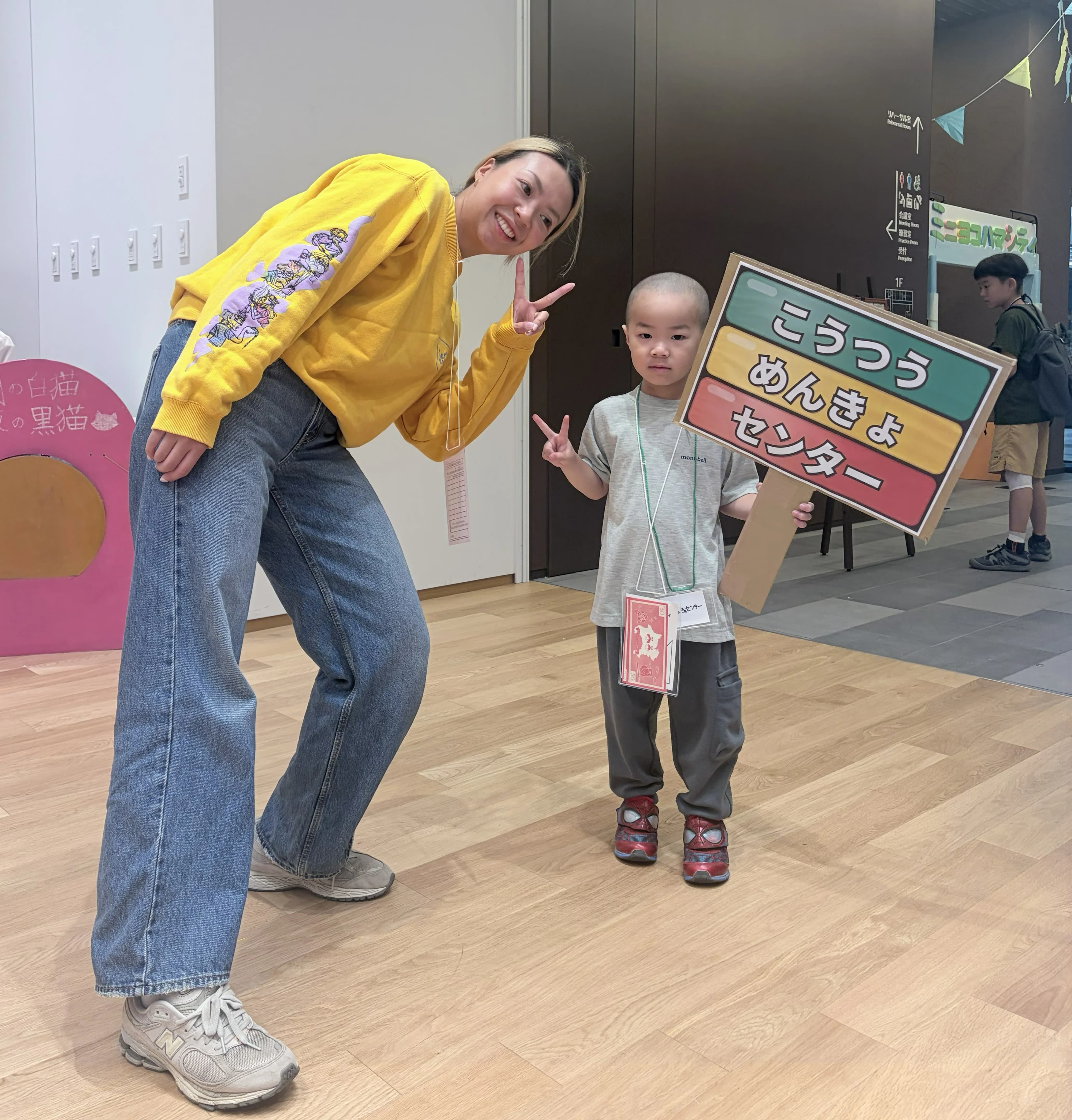 交通めんきょセンターの看板を持って呼びこみをする子どもとニコノリスタッフ